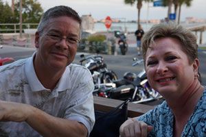 Couple at outdoor table with Boca Ciega Bay and evening sky behind them