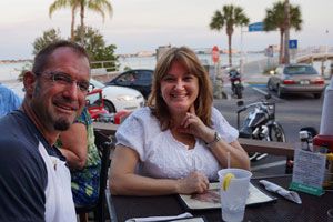 Couple enjoying dinner at an outdoor table at sunset with Boca Ciega Bay in the background