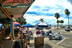 Wide-angle exterior of O'Maddy's with painted signage, blue umbrellas, and Shore Blvd