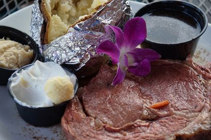 Prime rib with baked potato and orchid garnish