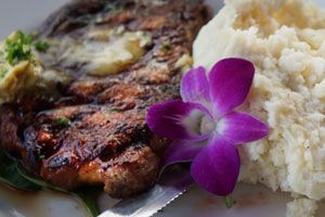 Grilled steak with orchid garnish and mashed potatoes