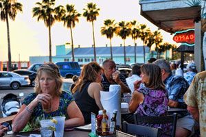 O'Maddy's outdoor patio at sunset with neon sign and palm trees