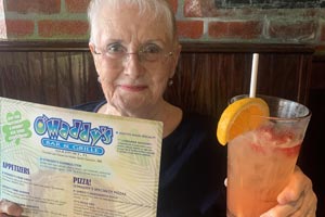 Regular patron with O'Maddy's menu and colorful cocktail